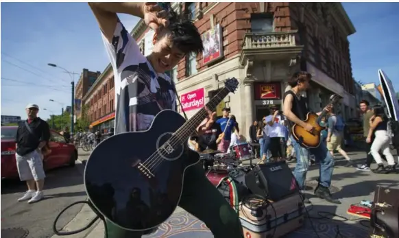  ?? CHRIS SO/TORONTO STAR PHOTOS ?? MunizO rocks out at Queen St. and Spadina Ave. The band had a major-label deal in their native Japan, but they gave it up to busk on the streets of Toronto and broaden their audience.