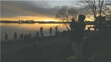  ?? ?? People are silhouette­d on the shoreline of Lake Ontario while taking in the solar eclipse at Lake Ontario Park on Monday. ELLIOT FERGUSON/THE KINGSTON WHIG-STANDARD