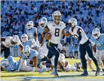  ?? GRANT HALVERSON / GETTY IMAGES ?? Georgia Tech’s Tobias Oliver scores the go-ahead touchdown against North Carolina on Saturday in Chapel Hill. The Yellow Jackets won 3828 to remain alive for an ACC division title.