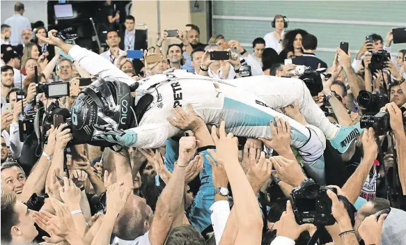  ?? Foto: AP ?? Triumf Nový šampion formule 1 Nico Rosberg se vznáší nad hlavami mechaniků stáje Mercedes poté, co po závěrečném závodu v Abú Zabí ovládl celkové pořadí mistrovstv­í světa.