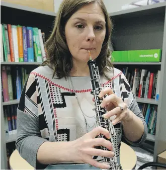  ?? LARRY WONG ?? Christine Guptill plays her oboe in her office at the University of Alberta on Monday. The professor of occupation­al therapy says orchestral musicians can overexert themselves during the festive season.