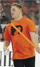  ??  ?? A member of the Philadelph­ia ice crew picks up debris thrown on the ice by Flyers fans in the third period Monday night.