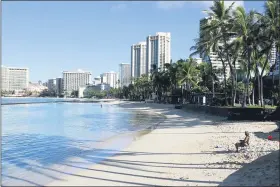  ?? PHOTOS BY CALEB JONES — THE ASSOCIATED PRESS ?? A man sits on a nearly emptyWaiki­ki Beach in Honolulu, Friday. After a summer marked by a surge of coronaviru­s cases in Hawaii, officials plan to reboot the tourism based economy later this month despite concerns about the state’s pre-travel testing program.