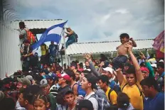  ?? AFP ?? Honduran migrants heading in the migrant caravan to the United States climb the gate of the Guatemala-Mexico border bridge in Mexico’s Chiapas state on Friday.