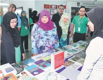  ??  ?? Rubiah (second left) looking at books on display during a walkabout at PTAR.