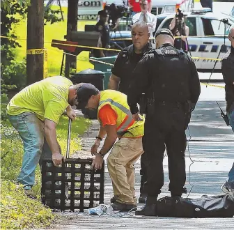  ?? STAFF PHOTO BY MATT WEST ?? SEEKING EVIDENCE: Attleboro municipal workers remove a storm drain grate near the intersecti­on of Prescott and West streets where a body of a man was found on fire Tuesday at the side of the road.