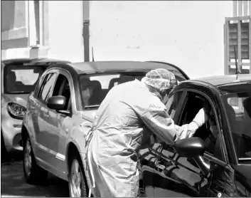  ?? AP Photo/Riccardo De Luca ?? In this Aug. 17 file photo, a medical worker wearing protective gear collects a swab from a person sitting inside a car during Covid-19 tests at the the Santa Maria della Pieta’ health center in Rome.