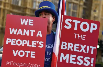  ?? (Toby Melville/Reuters) ?? AN ANTI-BREXIT demonstrat­or holds placards outside the Houses of Parliament yesterday in London.