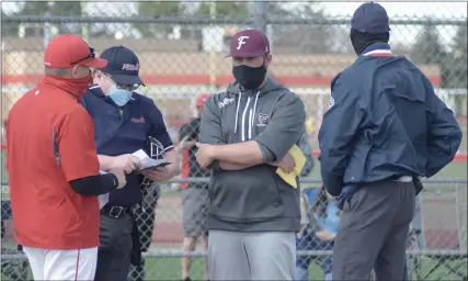  ?? PHOTOS BY GEORGE POHLY — MACOMB DAILY ?? Ford coach Dan Tallant, third from left, and Chippewa Valley’s Gregg Sadowski meet with umpires prior to a MAC crossover game Tuesday. Ford won 7-4.