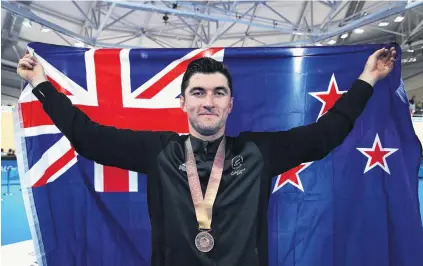  ??  ?? Celebratio­n time . . . Bronze medalist Dylan Kennett, of New Zealand, celebrates during the medal ceremony for the men’s 4000m individual pursuit at Anna Meares Velodrome in Brisbane last night(