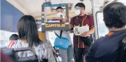  ?? ARIANA CUBILLOS/AP ?? Maximilian­o Bruzual reads “El Bus TV Capitolio” to commuters as Juan Pablo Lares holds a cardboard TV frame July 31 in Caracas, Venezuela.