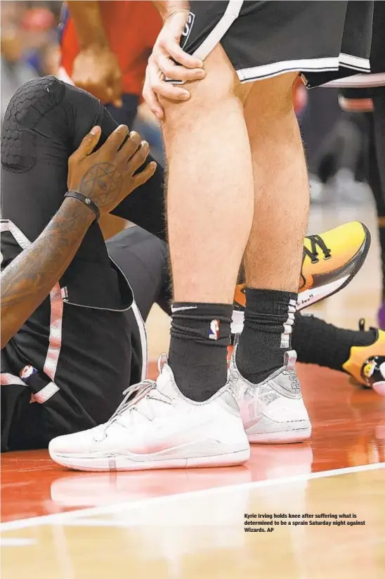  ??  ?? Kyrie Irving holds knee after suffering what is determined to be a sprain Saturday night against Wizards. AP