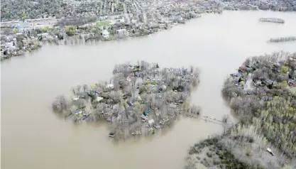  ??  ?? This aerial photo shows Ile Mercier, Quebec covered in floodwater on the Riviere des Prairies, on Monday. The bridge leading to the island is closed with its residents evacuated. — AP