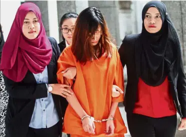  ??  ?? Under scrutiny: The legal assistant being led to the magistrate­s court in Putrajaya.
