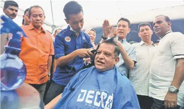  ?? — Bernama photo ?? Tengku Adnan getting a hair-cut after opening the Jom Bantu Rakyat programme at the Peoples Housing Scheme (PPR) in Kampung Baru Air Panas.