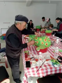  ??  ?? Yang Shaojin demonstrat­es how to paint the red dots on the frog’s yellow spots in his workshop in Yuxian County, Hebei Province in north China, on October 20