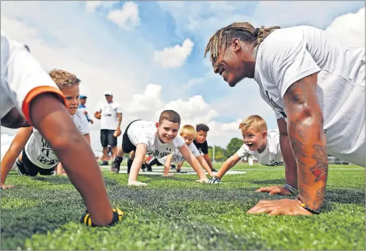  ?? [KYLE ROBERTSON/DISPATCH PHOTOS] ?? Former Westervill­e Central football star Benny Snell Jr. does pushups with kids after a drill during his football camp at Westervill­e Central on Thursday.