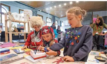  ?? FOTO: KERSTIN KRÄMER ?? Das Büchermeer im Konzertsaa­l der Alten Evangelisc­hen Kirche (v. l.): Die Geschwiste­r Lasare und Eliso Lomtadze (beide in georgische­r Tracht) und ihre Freundin Elene Naroushvil­i betreuen den Stand des Gastlandes Georgien.