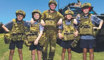  ?? TRYING ON: Ryan Catholic College students James Cassidy, 11, Dylan Casella, 11, Matthew Liessmann, 10, and Travis Booth, 11, with Gunner Andrew Milner at the school’s Defence Day. Picture: EVAN MORGAN ??