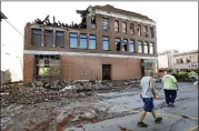  ?? CHARLIE NEIBERGALL / AP ?? Local residents walk past a tornado-damaged building Thursday on Main Street in Marshallto­wn, Iowa. Several buildings were damaged by a tornado that blew through the main business district in town, including the historic courthouse.