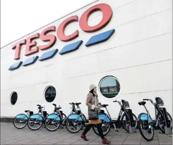  ?? PHOTO: REUTERS ?? A woman walks past a Tesco supermarke­t in central London. Tesco has been given the green light in a takeover bid for Booker.