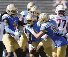  ?? RYAN SUN — THE ASSOCIATED PRESS ?? UCLA's Oluwafemi Oladejo, center, celebrates with teammates Saturday after intercepti­ng a pass from Washington State quarterbac­k Cameron Ward.