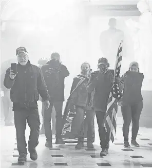  ?? SAUL LOEB/ AFP VIA GETTY IMAGES ?? Supporters of President Donald Trump make their way through clouds of tear gas in the corridors of the U. S. Capitol after they broke through police lines and entered the building.