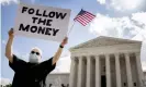  ??  ?? Bill Christeson holds up a sign that reads ‘Follow the Money’ outside the supreme court as it issued an initial ruling on the release of Donald Trump’s tax returns last July. Photograph: Andrew Harnik/AP