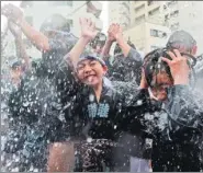  ?? TOSHIFUMI KITAMURA / AGENCE FRANCE-PRESSE ?? Residents carrying a portable shrine are splashed with water as they take part in the annual Fukagawa Hachimangu Festival in Tokyo on Sunday.