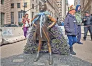  ?? KAREN MATTHEWS, AP ?? Wall Street’s “Fearless Girl” statue is draped with a bouquet of flowers to mark Internatio­nal Women’s Day on March 8 in New York. The statue, which has been a New York City tourist attraction since it was installed to mark Internatio­nal Women’s Day...