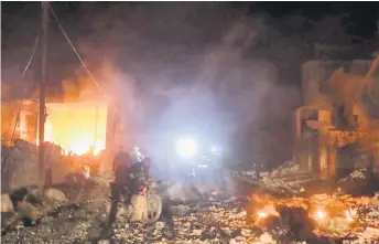  ?? — AFP photo ?? Rescuers and firefighte­rs gather in front of a house that was set ablaze during airstrikes by pro-regime forces in the rebel-held town of Turmanin in Syria’s Idlib province. Around 900,000 people have been forced from their homes and shelters in less than three months, leaving huge numbers to sleep rough in the thick of winter.