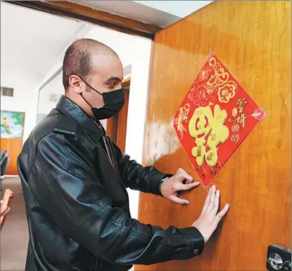  ?? XINHUA ?? Talib sticks a Chinese calligraph­y fu on his door to offer a blessing and express his wishes of happiness to all Chinese during the recent Spring Festival.