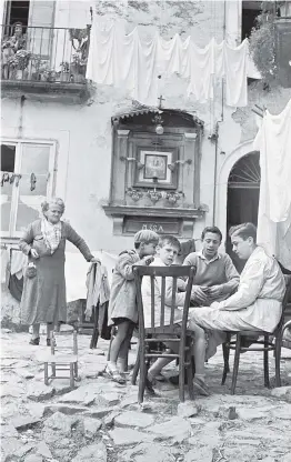  ??  ?? Innenhof im Neapel der 1950er-Jahre, ein Teffpunkt nicht nur der Jugendlich­en aus dem „Rione“(zu Deutsch: Viertel).