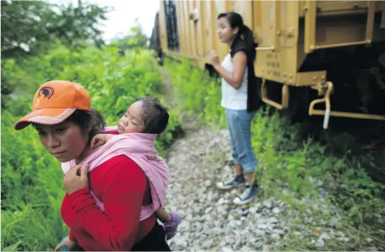  ?? REBECCA BLACKWELL/ THE ASSOCIATED PRESS ?? Aiming for the U.S., Guatemalan migrant Gladys Chinoy, 14, right, waits last Friday with more than 500 other migrants beside the stuck freight train on which they were travelling, outside Reforma de Pineda, Chiapas state, Mexico.