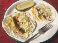  ?? (NWA Democrat-Gazette/Flip Putthoff) ?? These fish tacos are ready to fold after topping flour tortillas with a striped bass filet, cole slaw, chopped onion and grated cheddar cheese.