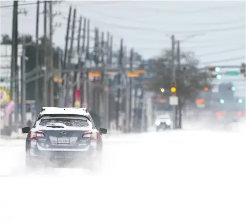  ?? DAVID J. PHILLIP / The ASSOCIATED PRESS ?? Vehicles drive on snow- and sleet-covered roads Monday in Spring, Texas, as a winter storm prompted a power
emergency and the shutdown of the largest oil refinery in North America in Port Arthur.