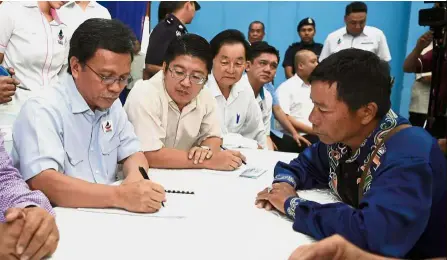  ??  ?? Up close and personal: Shafie noting down details being given by a resident in Keningau during the ‘Chief Minister with the Rakyat’ event. — Bernama