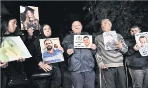  ?? AFP ?? Relatives carry portraits of victims of the 2020 Beirut port blast, as they protest in front of the residence of prosecutor general Ghassan Oueidat in Baabda, east of Beirut on Wednesday.