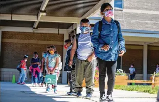  ?? ALYSSA POINTER / ALYSSA. POINTER@ AJC. COM ?? Students at Clarkdale Elementary School in Austell wait at a social distance as they prepare to board school buses back in October, before Cobb County schools converted to online- only instructio­n, which a new petition calls for.