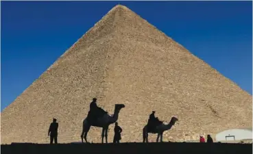  ?? AP PHOTO/HASSAN AMMAR ?? In 2012, policemen traverse the shade in front of the Great Pyramid in Giza, Egypt.