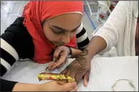  ?? Democrat-Gazette file photo ?? Mariam Khan (left) applies a temporary henna tattoo to the hand of Janecia Collins at the 2017 Little Rock Internatio­nal Food Festival.
