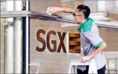  ?? AFP ?? A worker cleans the glass window of the SGX stock exchange building in Singapore .