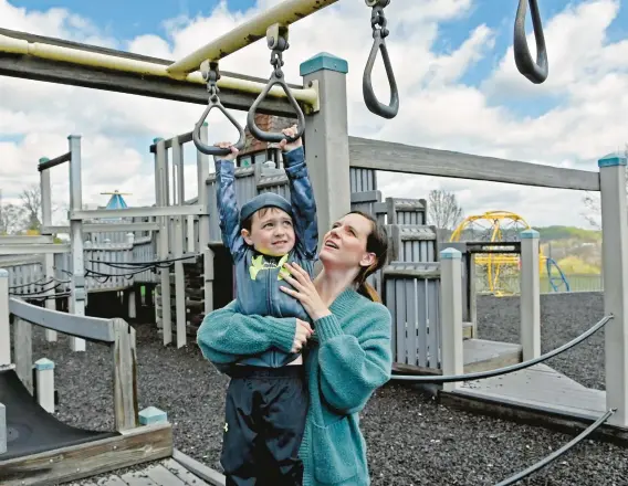  ?? KIM HAIRSTON/THE BALTIMORE SUN ?? Hillary Giddings helps her son, Michael, 4, as he navigates a ring bridge in Annie’s Playground at Edgeley Grove Park.