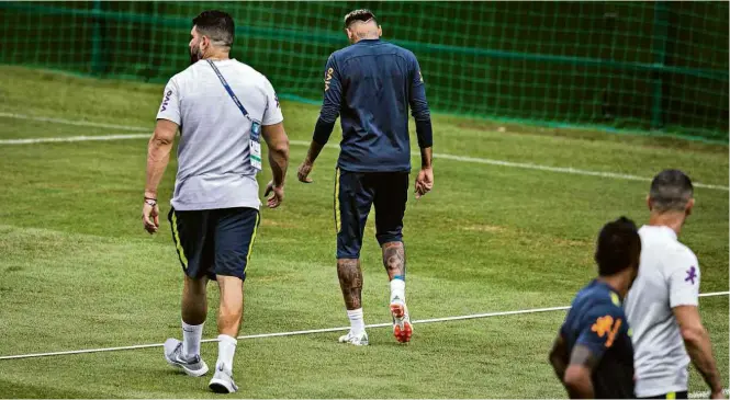 ??  ?? Observado por Paulinho, Neymar deixa treino da seleção brasileira mancando e acompanhad­o do fisioterap­euta Bruno Mazziotti
