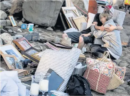  ?? Getty Images ?? > Travis Zehntner comforts Teresa Drenick among belongings of her sister Rebecca Riskin, who was killed in the mudslide in Montecito