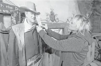  ?? Marvin Pfeiffer / San Antonio Express-News ?? Tammy Pullen, with The Nest Sale Services and Liquidatio­n, puts a price tag on a life-size cutout of John Wayne in the Cantina at Alamo Village near Brackettvi­lle. About 2,400 items are being liquidated from the movie set, where 72 motion pictures were...