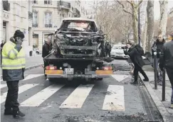  ??  ?? 0 A burnt-out car is removed from a Paris street yesterday