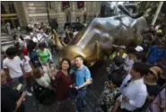  ?? MARK LENNIHAN — THE ASSOCIATED PRESS FILE PHOTO ?? On July 31, tourists crowd around the Charging Bull statue in New York’s financial district to take photos. Whether you’re planning a trip to a country across the globe or packing the car for a weekend road trip to a local campground, you can have a debt-free vacation with some careful planning.