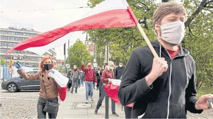  ?? BLOOMBERG ?? Protesters wear protective masks and wave Polish national flags on Thursday during a march to protest the presidenti­al election in Wroclaw, Poland.