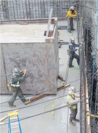  ?? ADRIAN LAM, TIMES COLONIST ?? Constructi­on workers wire together rods of rebar at a condominiu­m constructi­on site at the corner of Johnson and Vancouver streets downtown.